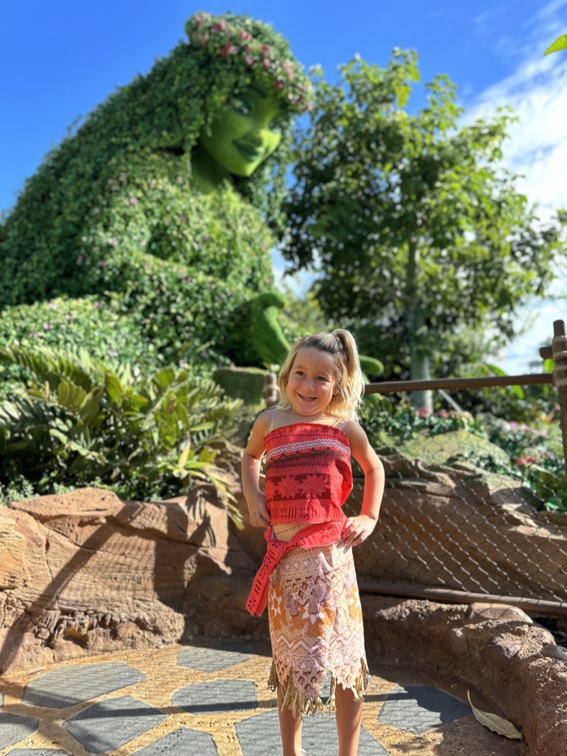 A girl in the mermaid dress on a porch holding a wand.